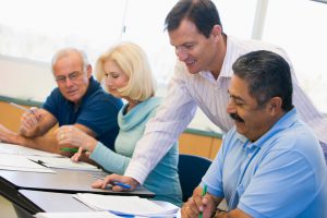 Teacher assisting mature student with work in class